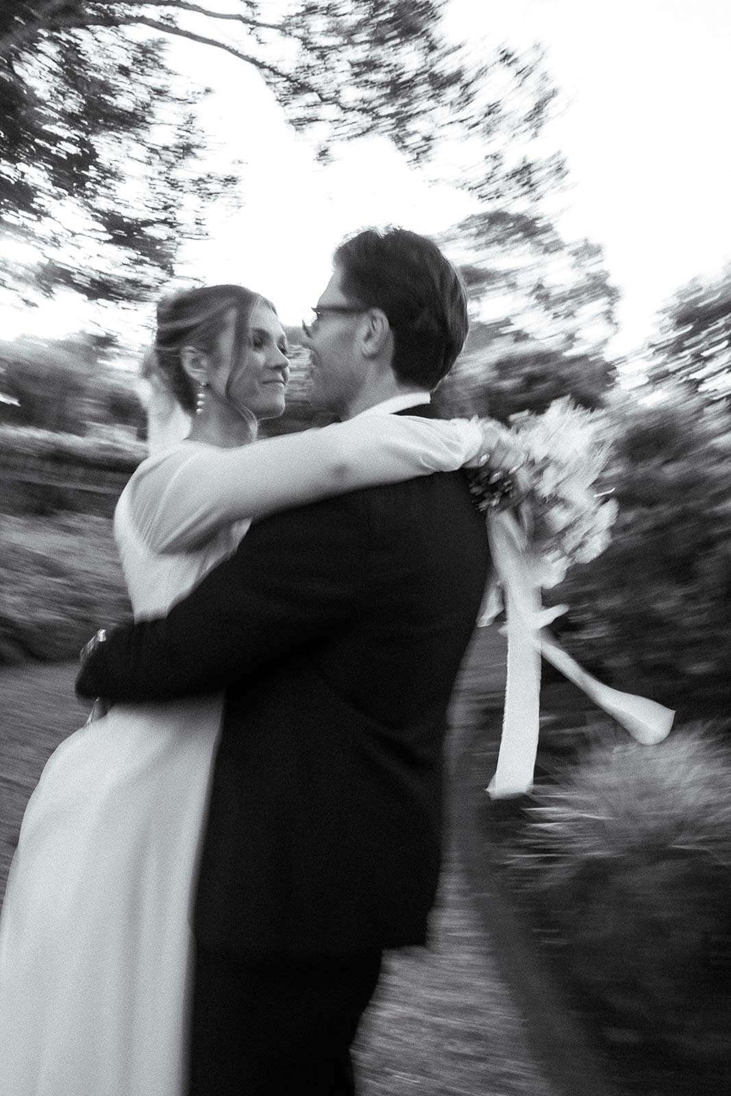 Bride and groom dancing in the gardens with motion blur